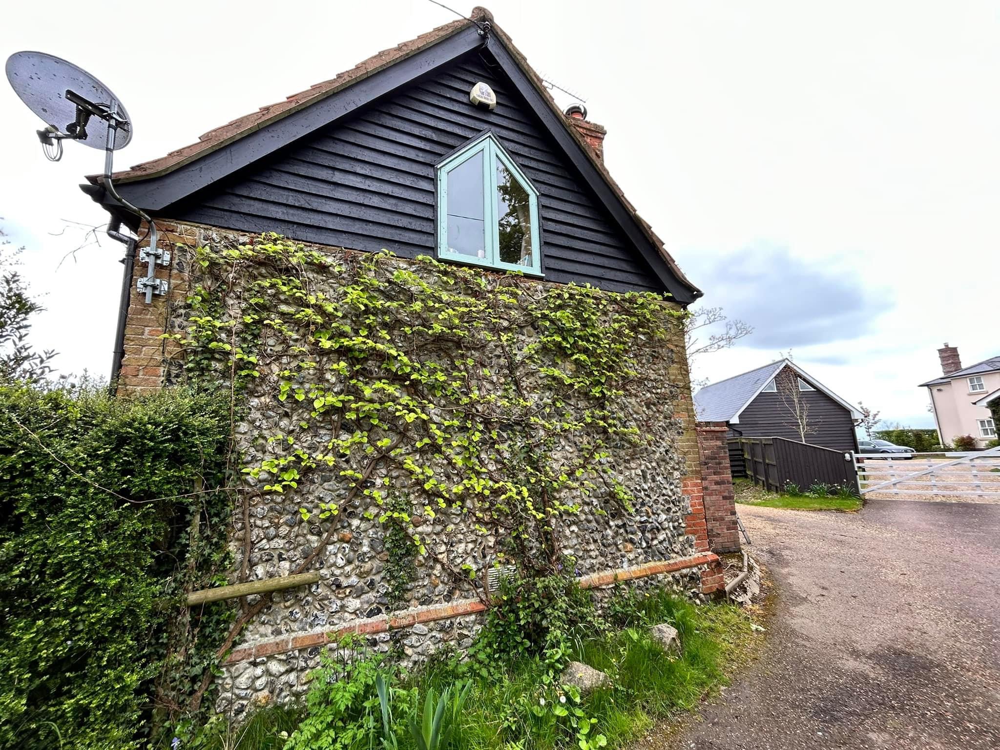 Black boarded gable above an old flint wall