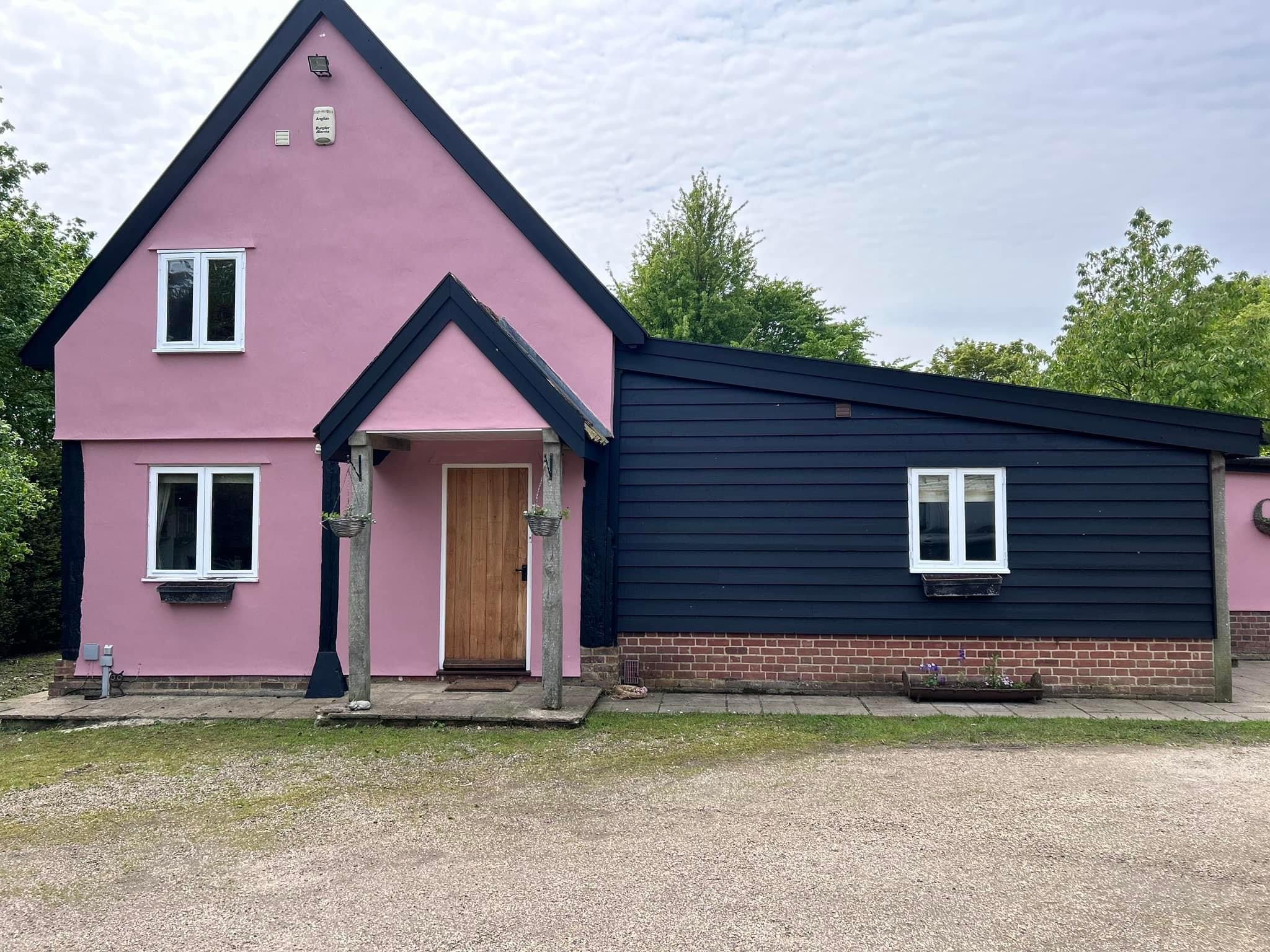 Suffolk pink cottage with a black weatherboarded wing, freshly painted