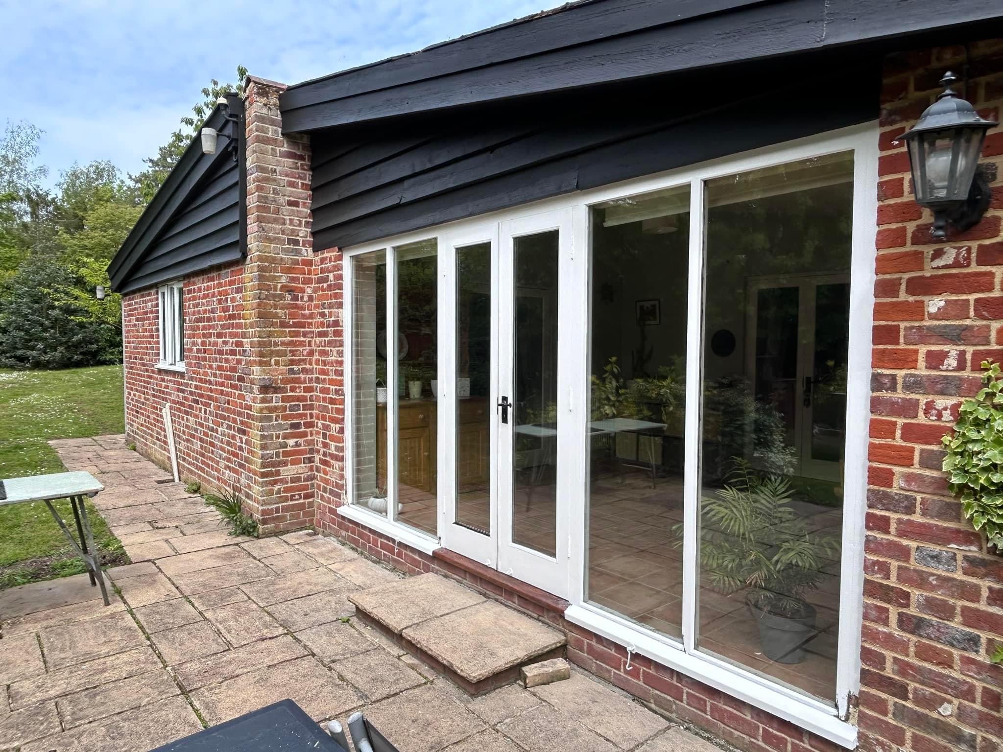 Brick and black boarded extension with white French doors