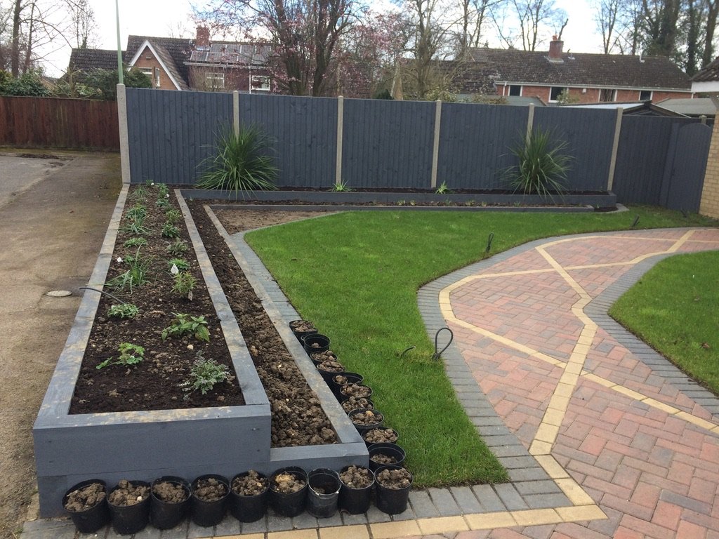 Landscaped garden with a raised bed, lawn and block paved path