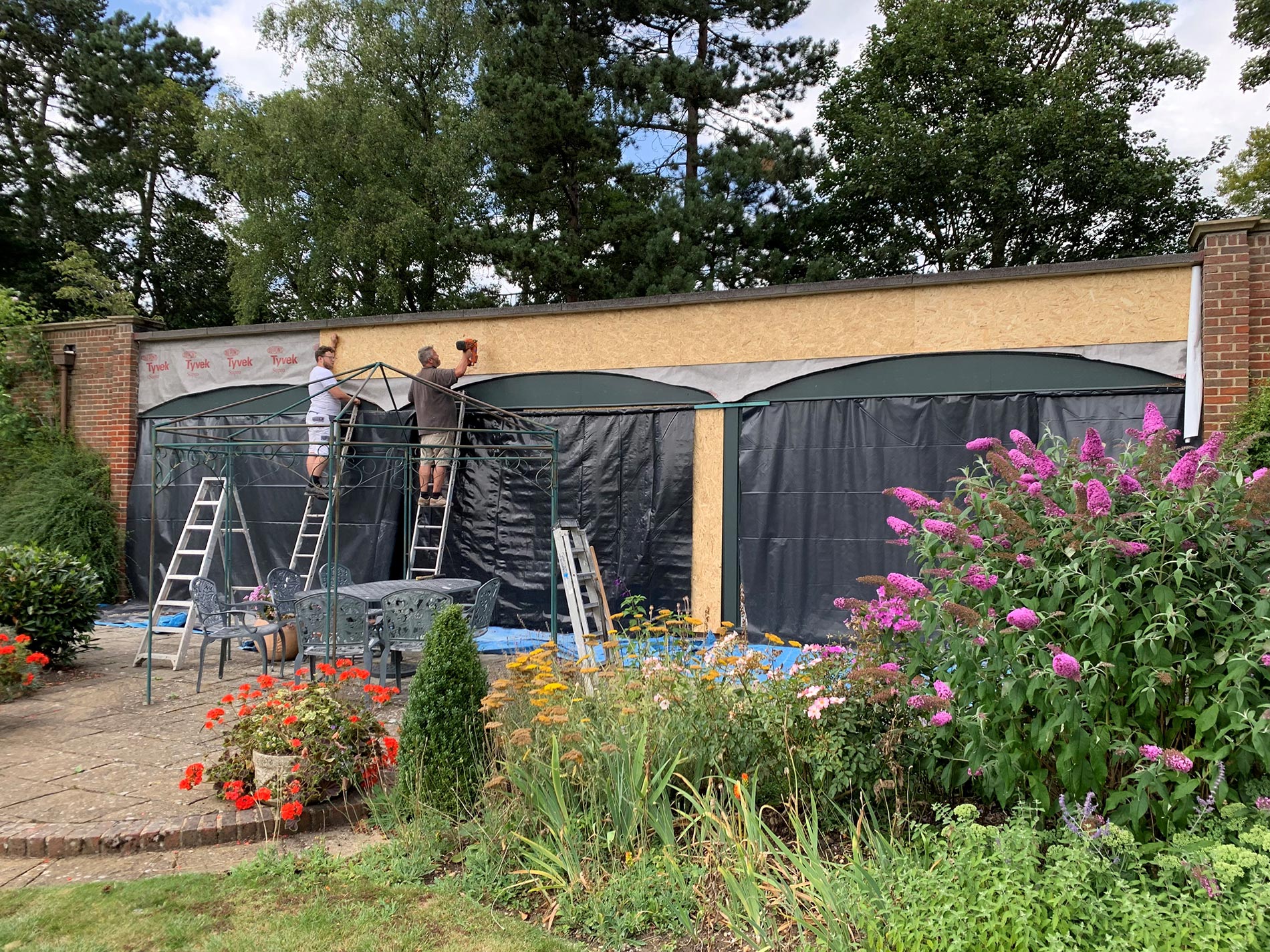 The same pool house during repairs, sheeted and laddered